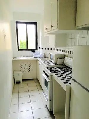 a white kitchen with a stove and a window at Stylish Montreal Apartment: Comfortable Stay in the Golden Square Mile in Montréal