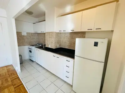 a kitchen with white cabinets and a refrigerator at Stylish Montreal Apartment: Comfortable Stay in the Golden Square Mile in Montréal