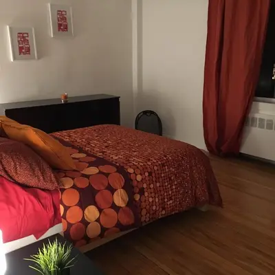 a bedroom with a bed with a red comforter at Stylish Montreal Apartment: Comfortable Stay in the Golden Square Mile in Montréal