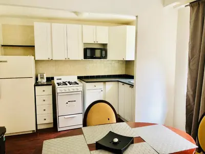 a small kitchen with white cabinets and a table at Stylish Montreal Apartment: Comfortable Stay in the Golden Square Mile in Montréal