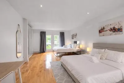 a white room with two beds and a table at Loft The White Pearl Plateau-Mont-Royal 3 Beds in Montréal