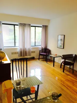 a living room with a table and chairs and windows at Stylish Montreal Apartment: Comfortable Stay in the Golden Square Mile in Montréal