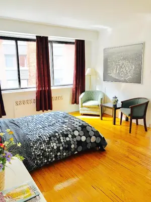 a bedroom with a bed and a chair and windows at Stylish Montreal Apartment: Comfortable Stay in the Golden Square Mile in Montréal