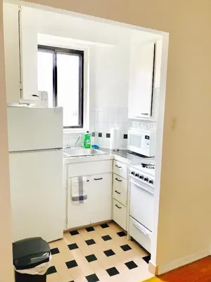 a kitchen with white appliances and a checkered floor at Stylish Montreal Apartment: Comfortable Stay in the Golden Square Mile in Montréal