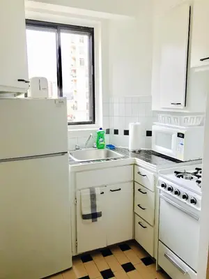 a white kitchen with a sink and a refrigerator at Stylish Montreal Apartment: Comfortable Stay in the Golden Square Mile in Montréal