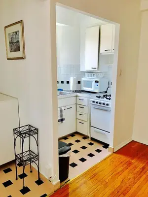 a kitchen with white appliances and a black and white checkered floor at Stylish Montreal Apartment: Comfortable Stay in the Golden Square Mile in Montréal