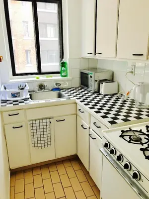 a white kitchen with a sink and a stove at Stylish Montreal Apartment: Comfortable Stay in the Golden Square Mile in Montréal