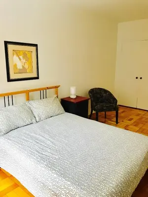 a bedroom with a large bed and a chair at Stylish Montreal Apartment: Comfortable Stay in the Golden Square Mile in Montréal