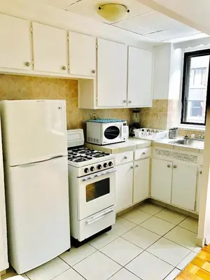 a kitchen with white appliances and white cabinets at Stylish Montreal Apartment: Comfortable Stay in the Golden Square Mile in Montréal