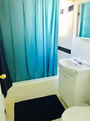 a bathroom with a blue shower curtain and a sink at Stylish Montreal Apartment: Comfortable Stay in the Golden Square Mile in Montréal