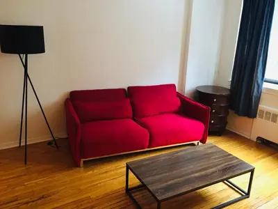 a red couch in a living room with a table at Stylish Montreal Apartment: Comfortable Stay in the Golden Square Mile in Montréal