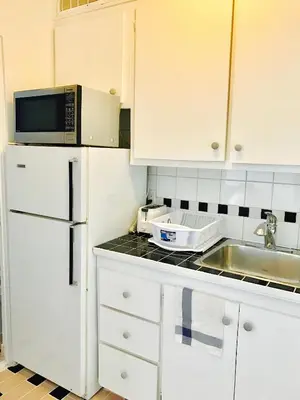a kitchen with white cabinets and a sink and a microwave at Stylish Montreal Apartment: Comfortable Stay in the Golden Square Mile in Montréal