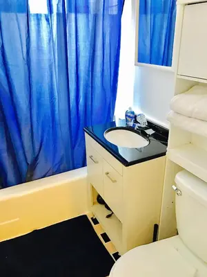 a bathroom with a sink and a blue shower curtain at Stylish Montreal Apartment: Comfortable Stay in the Golden Square Mile in Montréal