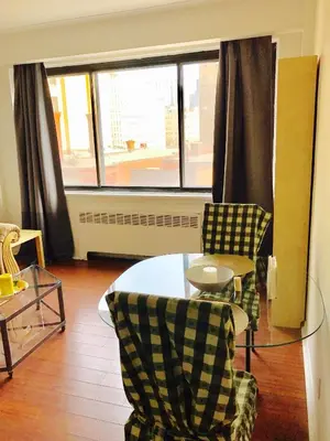 a living room with a table and chairs and a window at Stylish Montreal Apartment: Comfortable Stay in the Golden Square Mile in Montréal