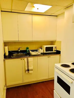 a kitchen with white cabinets and a sink and a microwave at Stylish Montreal Apartment: Comfortable Stay in the Golden Square Mile in Montréal