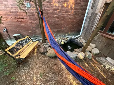 a hammock in a backyard with a pond at L'Oasis Des Nomades in Trois-Rivières