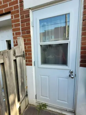 a blue door with a window next to a brick building at Logement complet, proche métro, parking gratuit in Montréal