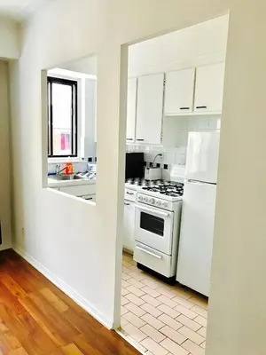 a white kitchen with a stove and a refrigerator at Stylish Montreal Apartment: Comfortable Stay in the Golden Square Mile in Montréal