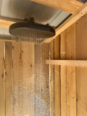 a shower with water on a wooden wall at Chalet BIA - Le Petit Chaleureux in Ham Nord