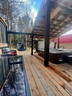 a wooden deck with a hot tub and a hot tub at Chalet BIA - Le Petit Chaleureux in Ham Nord