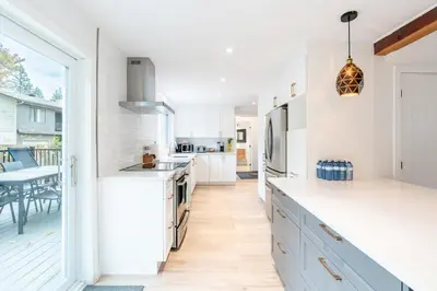 a kitchen with white cabinets and a large window at lacbrome Chalet lake+Terrasse+BBQ+Hot-tub in Lac-Brome