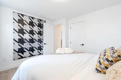 a white bedroom with a large bed with a black and white wall at lacbrome Chalet lake+Terrasse+BBQ+Hot-tub in Lac-Brome