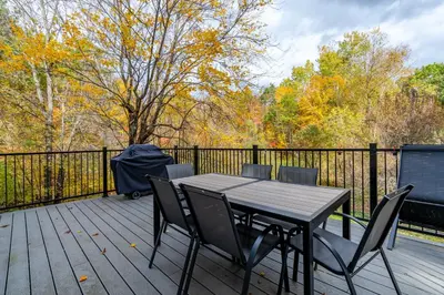 a table and chairs on a deck with a fence at lacbrome Chalet lake+Terrasse+BBQ+Hot-tub in Lac-Brome