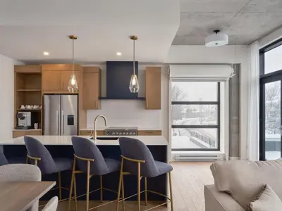 a kitchen with blue chairs and a kitchen island at Hôtel Expérience - Quartier Des Marinas in Magog-Orford
