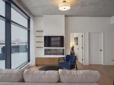a living room with a couch and a tv at Hôtel Expérience - Quartier Des Marinas in Magog-Orford