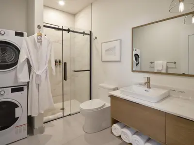 a bathroom with a sink toilet and a washing machine at Hôtel Expérience - Quartier Des Marinas in Magog-Orford
