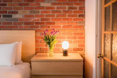 a vase of flowers on a table next to a brick wall at Bed and Breakfast du Village BBV in Montréal