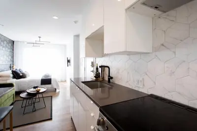 a kitchen with white cabinets and a living room at 6768 - 202 Amazing mini studio with full kitchen by Denstays in Montréal