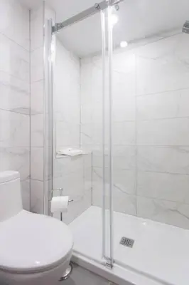 a white bathroom with a shower and a toilet at 6768 - 202 Amazing mini studio with full kitchen by Denstays in Montréal