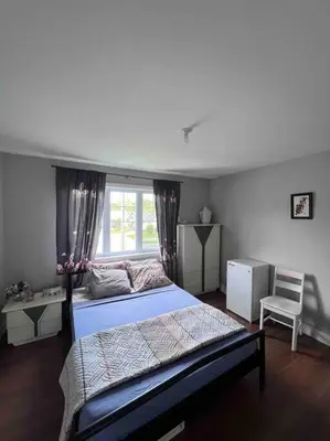 a bedroom with a bed and a window and a chair at Maison chaleureuse, énergétique et florale in Sherbrooke