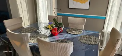 a dining room table with chairs and a glass table with flowers at Maison chaleureuse, énergétique et florale in Sherbrooke