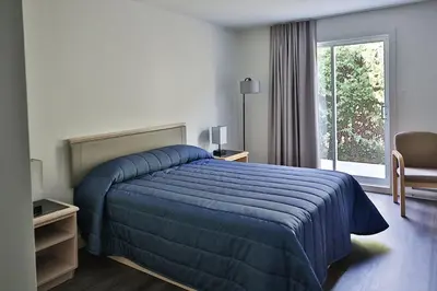 a hotel room with a blue bed and a window at Motel Mascouche in Mascouche