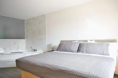 a white bedroom with a bed and a sink at Motel Mascouche in Mascouche