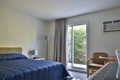 a bedroom with a blue bed and a large window at Motel Mascouche in Mascouche