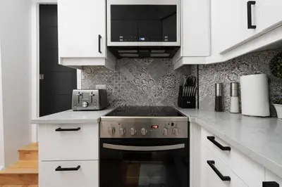 a kitchen with white cabinets and a stove top oven at Downtown Luxe: Metro, King Bed, Parking, Sleeps 6 in Montréal