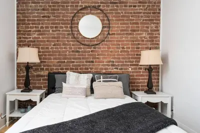 a bedroom with a brick wall and a bed with two lamps at Downtown Luxe: Metro, King Bed, Parking, Sleeps 6 in Montréal