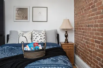 a bed with a basket on it next to a brick wall at Downtown Luxe: Metro, King Bed, Parking, Sleeps 6 in Montréal