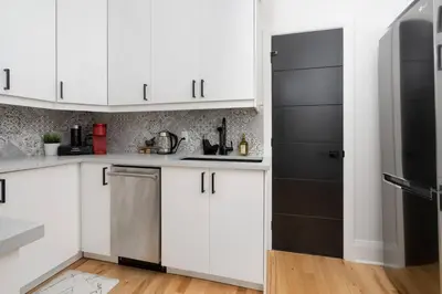 a kitchen with white cabinets and a black refrigerator at Downtown Luxe: Metro, King Bed, Parking, Sleeps 6 in Montréal