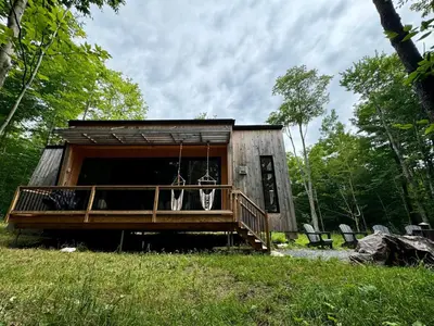a small cabin with a porch and a porch swing at Cottage Zoobox-style 51 in Eastman