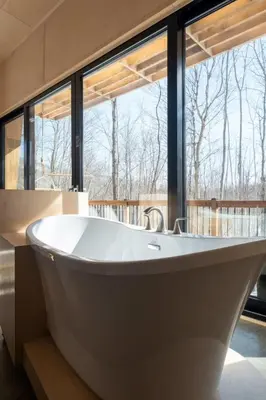 a large white bath tub in a room with windows at Cottage Zoobox-style 51 in Eastman