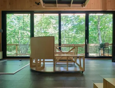 a wooden chair sitting in a room with windows at Cabin Zoobox 57 in Eastman
