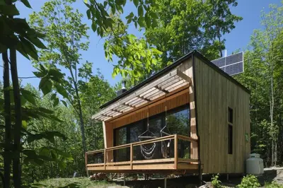 a tiny house in the woods with a solar roof at Cabin Zoobox 75 in Eastman