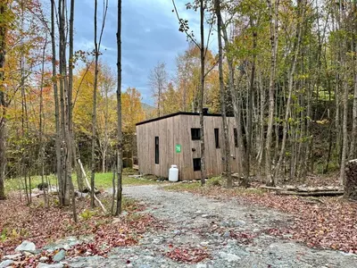 a barn in the woods with a dirt road at Cabin Zoobox 76 in Eastman