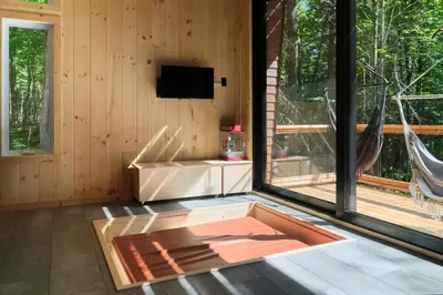 a living room with a tv and a large window at Cabin Zoobox 78 in Eastman