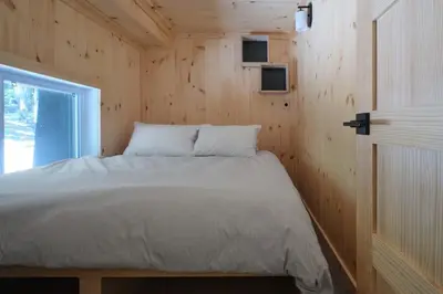 a bed in a wooden room with a window at Cabin Zoobox 78 in Eastman