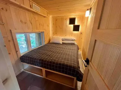 a small bed in a wooden room with a window at Cabin Zoobox 79 in Eastman